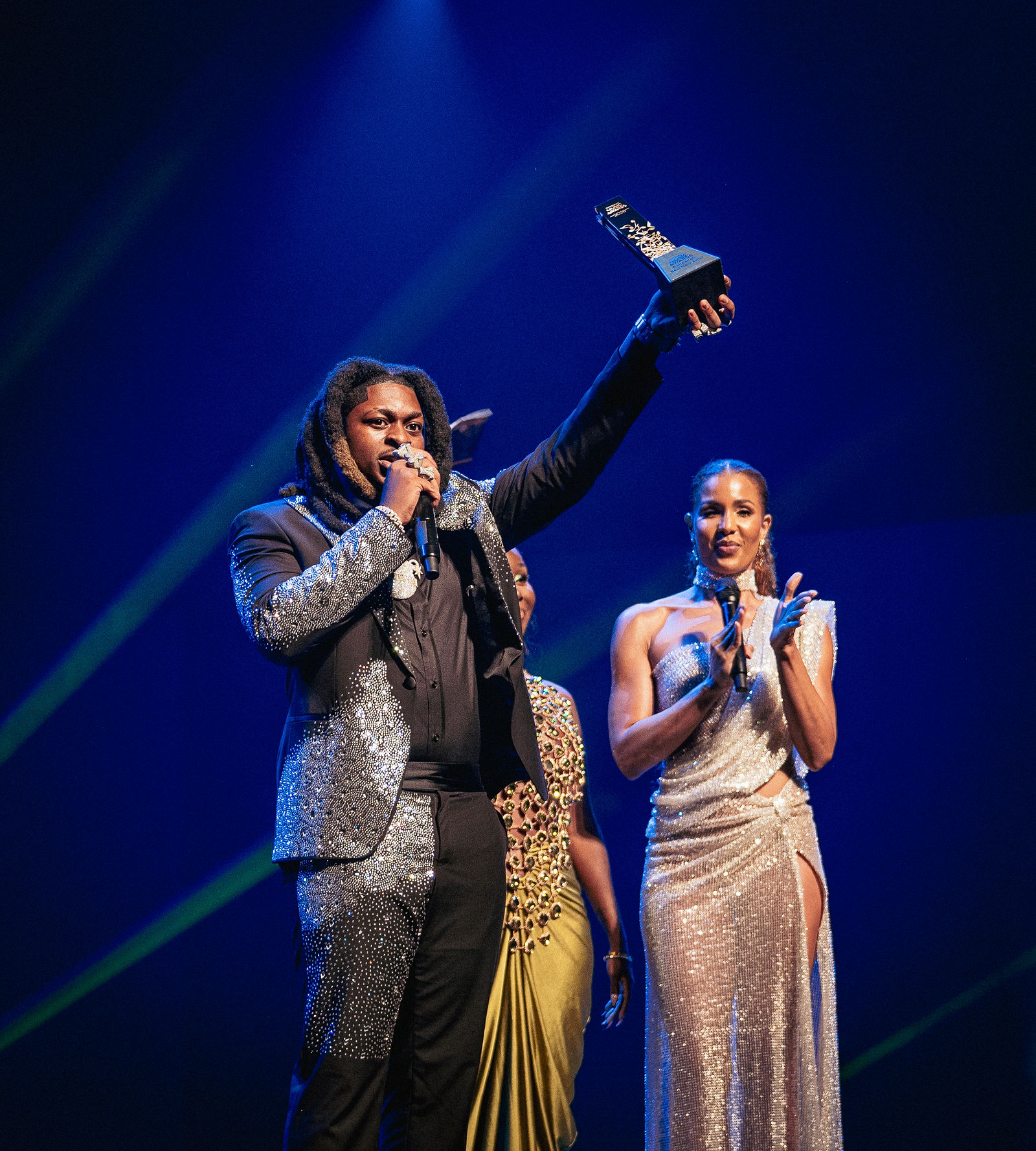 An award recipient raising his trophy on the Caribbean Music Awards stage